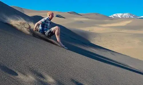 Man Sand Sledding on a Dune