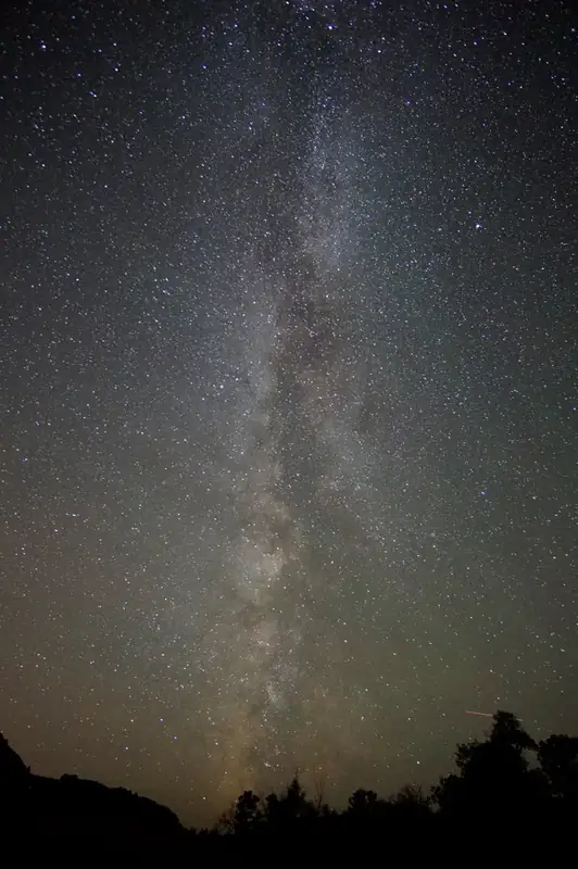 the swirling, dusty looking milky way runs vertically though a starry night sky